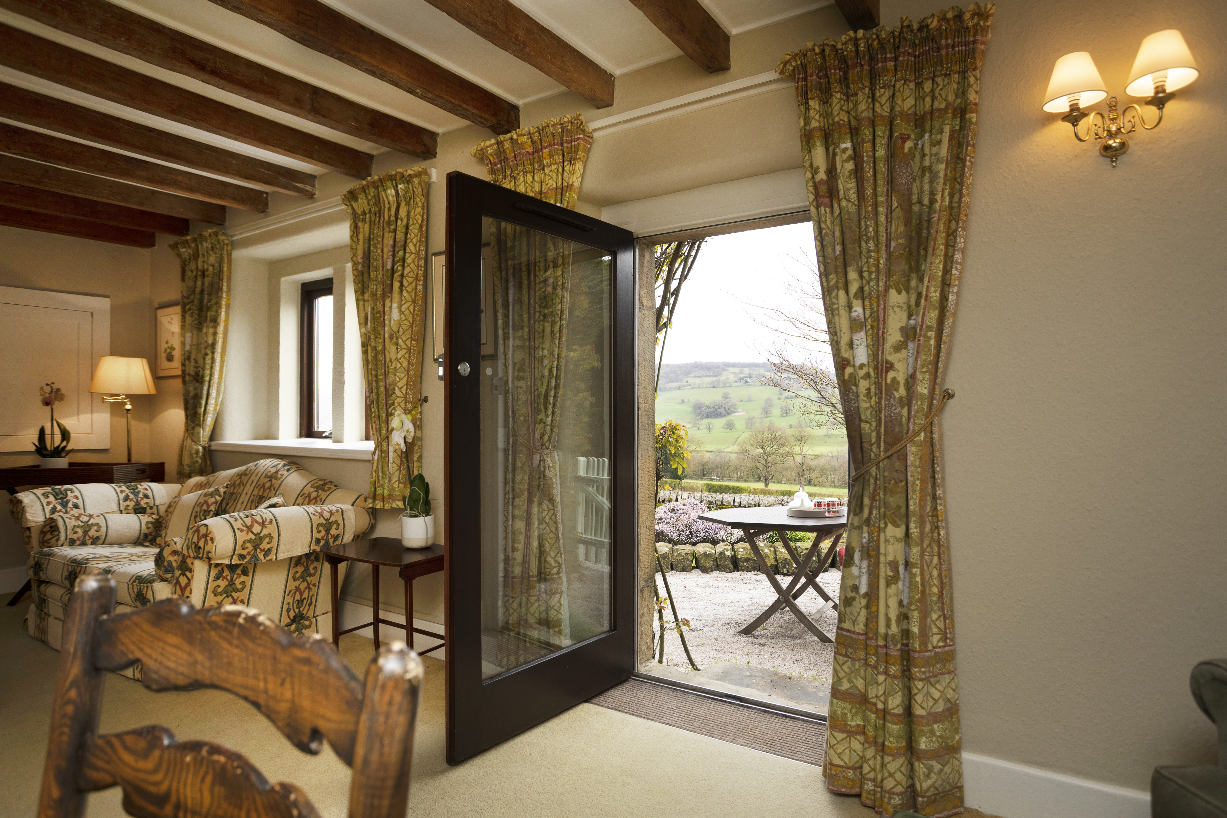 French doors open onto the patio and garden seating at Woodside Cottage