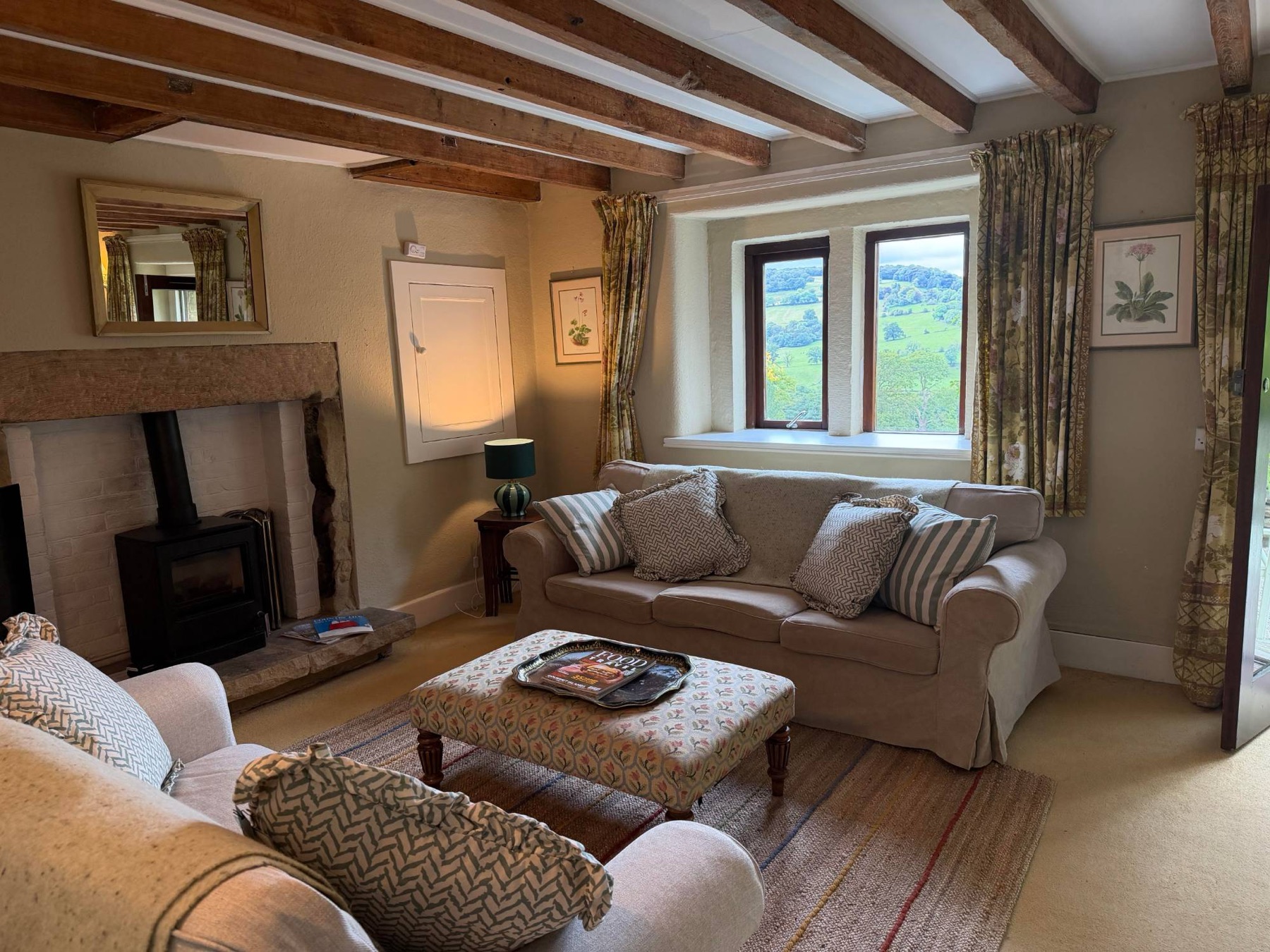 The sitting room at Woodside Cottage, sofa beneath a window looking over the hills
